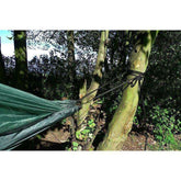 Strong webbing fixed to trees for a hammock setup, showcasing its grip and versatility for camping.